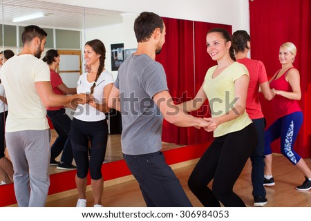 Happy men and women enjoying active dance at a dance studio