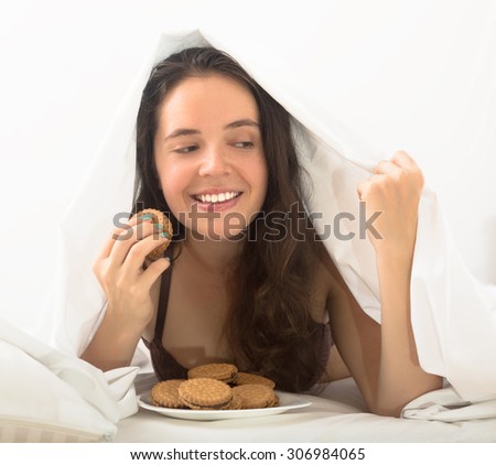 woman eating sweet chocolate chip cookies in bed at home