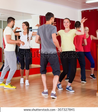 Happy men and women enjoying active dance at dance studio