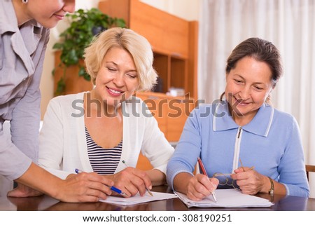 Happy smiling female pensioners signing documents with public notary