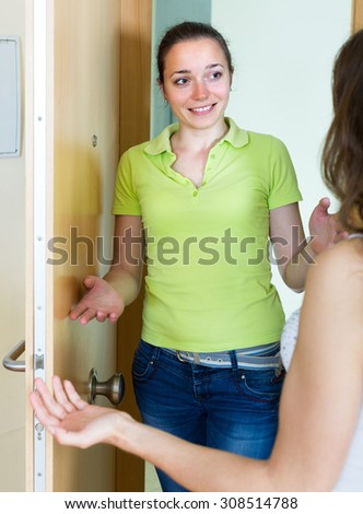 Joyful smiling young woman meeting girlfriend at the door