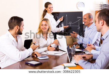 Smiling female expert makes a presentation at a meeting in the office. Focus on the left woman