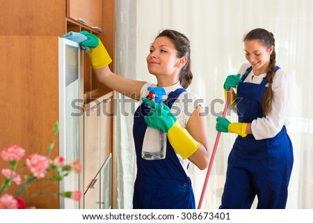 Smiling professional cleaners team cleaning in the house with rags and mop. Selective focus