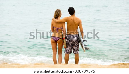 Happy couple running on the beach with surf boards