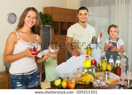 Happy middle-class family of four with bags of food at home