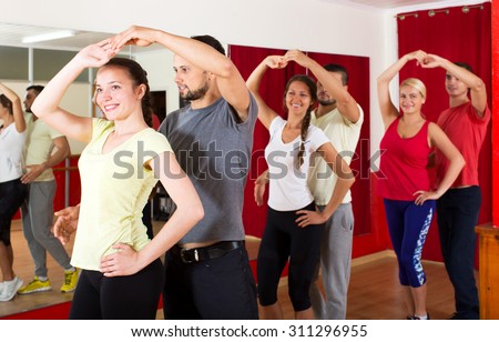 Smiling young people dancing Latino dance in class