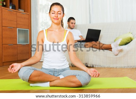 Relaxed girl in yoga position and lazy guy on sofa at home