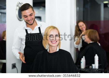 Hair stylist working on haircut for young woman. Focus on the woman