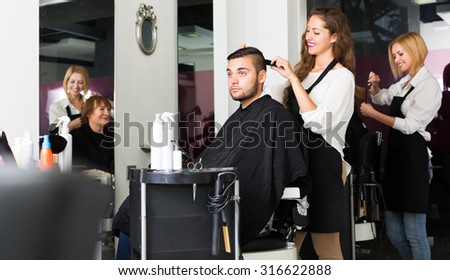 Beauty woman hairdresser doing hairstyle for young men