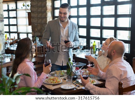 Portrait of happy young adults having dinner in family restaurant. Focus on young man
