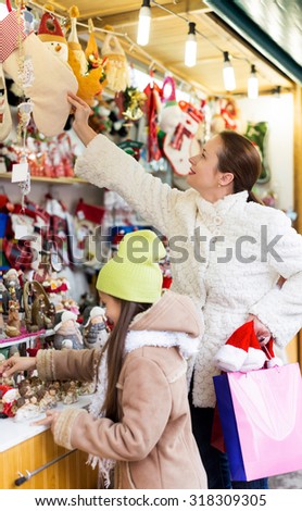 woman with little daughter looking at counter of Christmas market. Focus on mother