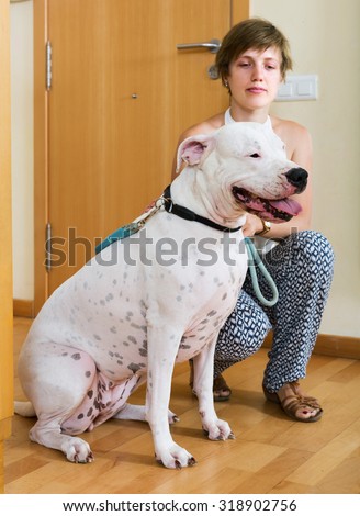 Attractive girl with white big dog on leash indoor. Focus on dog
