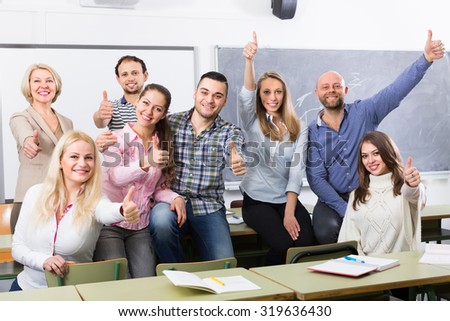 Smiling professor and cheerful students posing in classroom at extension courses