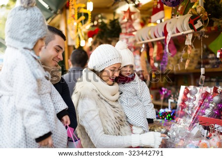 Family couple with children choosing Christmas decoration at fair. Shallow focus. Focus on woman.