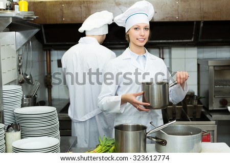 Positive head-cooks cooking at professional kitchen in the restaurant