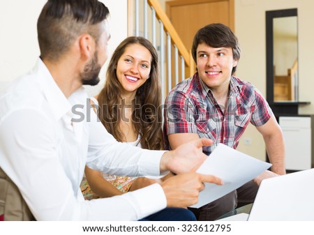 Smiling salesman talking with young man and woman about purchase at their home