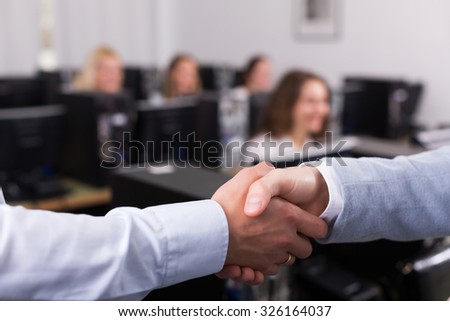 Satisfied adult customer service manager shaking hand of employee