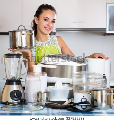 Portrait of smiling adult girl with kitchen appliances at home