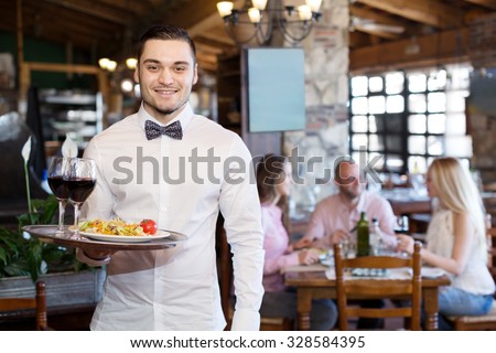Portrait of a happy male waiter with a tray in his hand at the restaurant