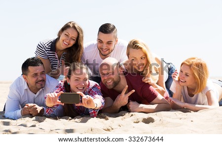 Cheerful friends of different age doing selfie at sea shore