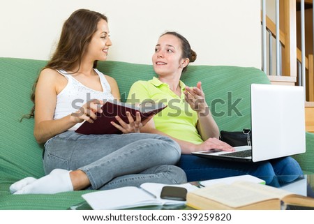Two young happy girls studying at home