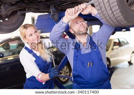 Handsome american mechanic and female assistant working at auto repair shop