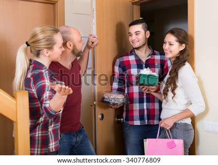 Happy smiling guests with cake and presents standing in doorway. Focus on girl