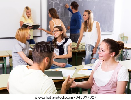 Friendly adult students chatting while sitting in the room. Focus on the right woman