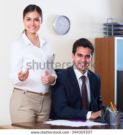 Smiling businessman and secretary working in modern office