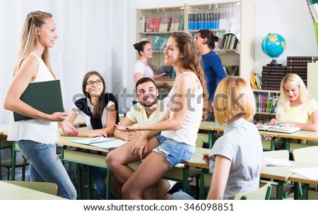 Several smiling students having a conversation sitting in the classroom