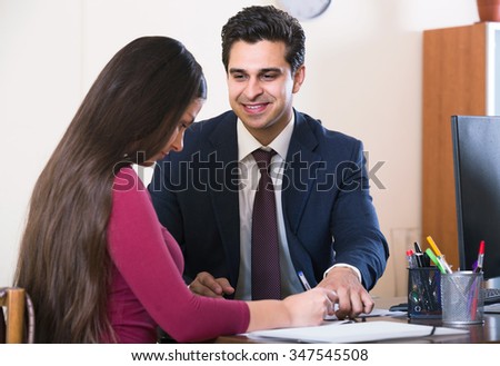 Banking agent listening to young european customer and smiling in agency