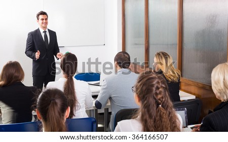 Group of attentive adult students with teacher in classroom at business training
