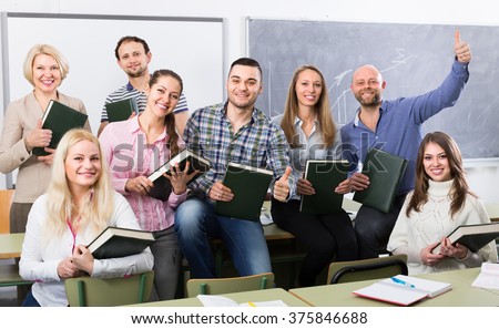 Group of cheerful adult students and coach posing at training session school. Selective focus