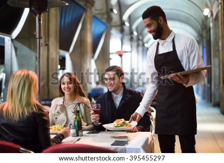smiling american afro waiter taking table order and smiling in winter evening