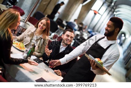 Black waiter serving terrace restaurant guests at table.Focus on the man