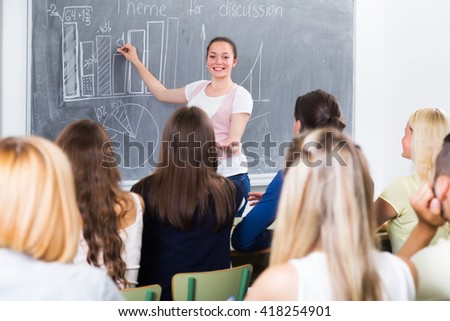 Ecxited young student gives answer near blackboard during lesson