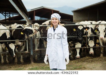 Portrait of female vet working with cows in farm outdoors