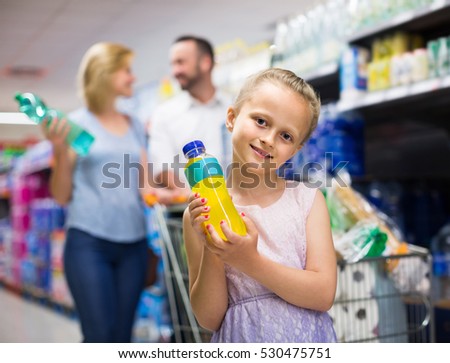 Portrait of smiling girl holding plastic bottle with water in grocery shop