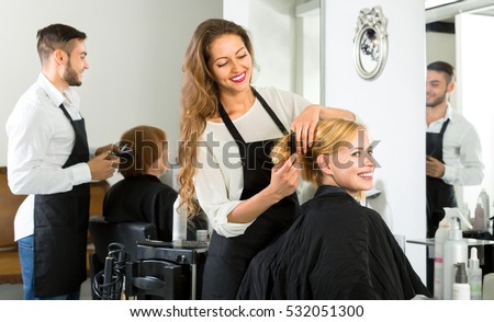 Female barber combing woman\'s hair at a hair salon