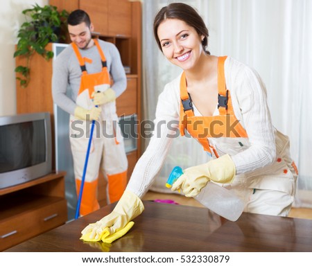 Happy professional cleaners with equipment clean furniture of client house