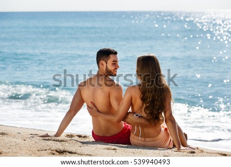 Young couple laying on sandy beach at sea shore in the sunny day