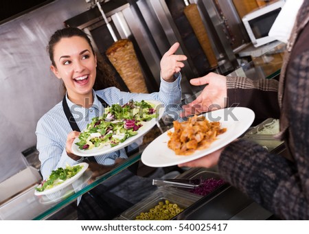 Happy young brunette girl and satisfied customer buying kebab