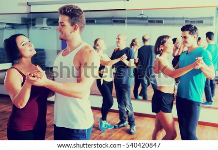 Cheerful dancing couples learning salsa at dance class
