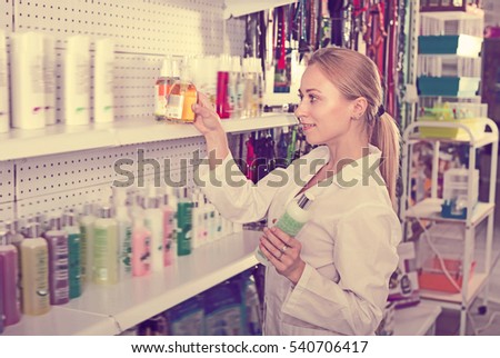 Female shop assistant offering shampoo for pets in pet shop