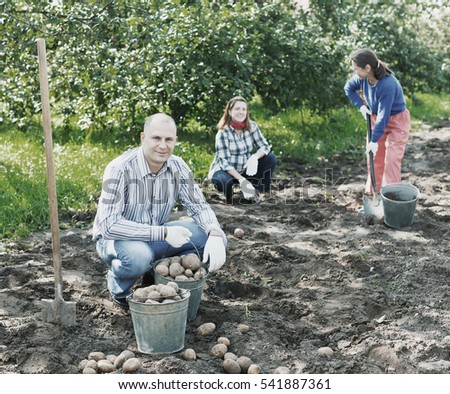 family harvesting potatoes in vegetable garden