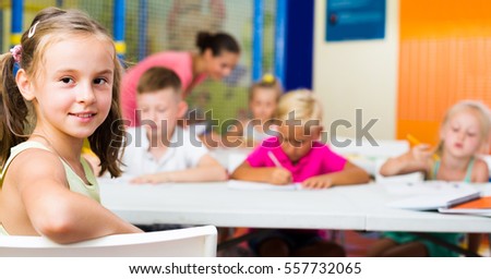 Portrait of joyful smiling  little school girl  sitting at lesson