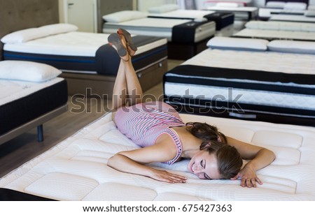 Sexy female lying on new mattress in  furniture store and  shopping