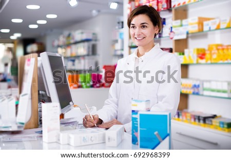 Smiling pharmacist ready to assist in choosing at counter in pharmacy