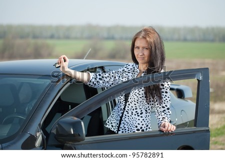 Smiling woman get in the car and looking at camera