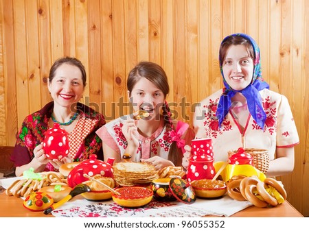 Women in traditional  clothes eats pancake with tea during  Shrovetide
